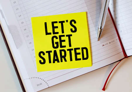 Let's get started word on white ring binder notebook with hand holding pencil on wood table, Business concept.の写真素材