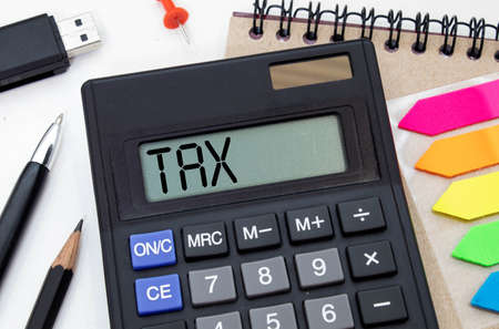Business concept - TAX word on calculator on white desk.の写真素材