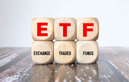 ETF, Exchange Traded Fund, realtime mutual index fund that can trade in equity stock market, cube wooden block with alphabet building the word ETF on grid line paper, random block in the background.の写真素材