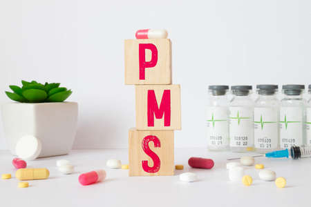 a group of white and red pills and cubes with the word PMS Premenstrual syndrome on them, white background. Concept carehealth, treatment, therapy.の写真素材