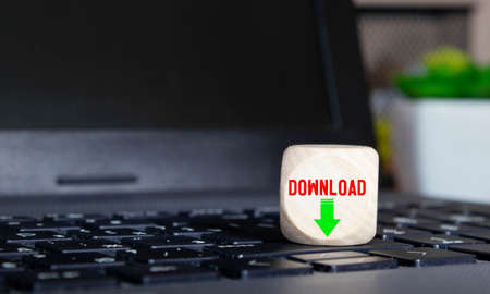 Conceptual Download Text with Arrow Down on Small Wooden Cube Above Computer Keyboard. Isolated on White.の写真素材