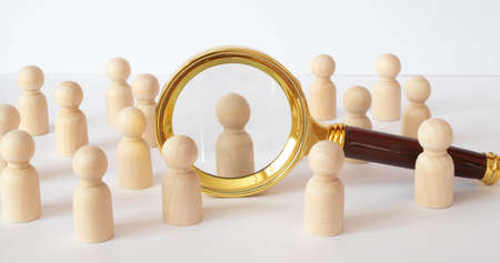 The chosen person among others. A human figure of red color stands out from the crowd. Wooden figures of people. A talented worker, a successful choice. Promotion. Concept of search for worker.の写真素材