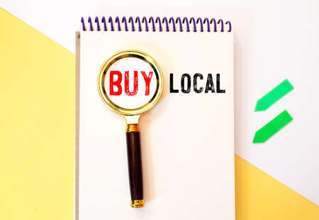 Finance and business concept. On a white background lies a calculator and a magnifying glass with the inscription - Buy Localの写真素材