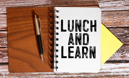 Lunch and Learn, A spiral Notepad that has the words Lunch and Learn over a distressed wood background.の写真素材