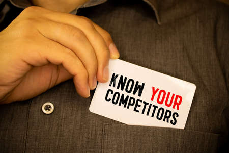 Businessman putting a card with text know your competitors in the pocket.の写真素材
