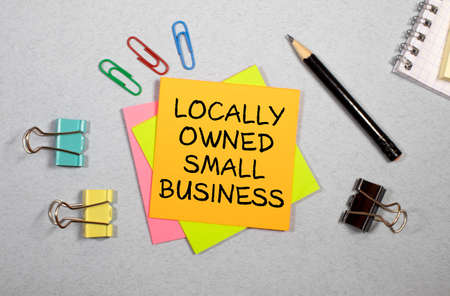 Closeup on businessman holding a card with text LOCALLY OWNED SMALL BUSINESS, business concept image with soft focus background and vintage toneの写真素材