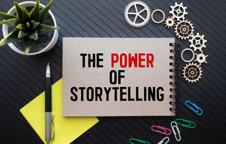 Business concept. Notebook with text THE POWER OF STORYTELLING sheet of white paper for notes, glasses in the white background.の写真素材