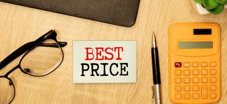 Text BEST PRICE on a white notepad with pencils on a wooden background. Business conceptの写真素材