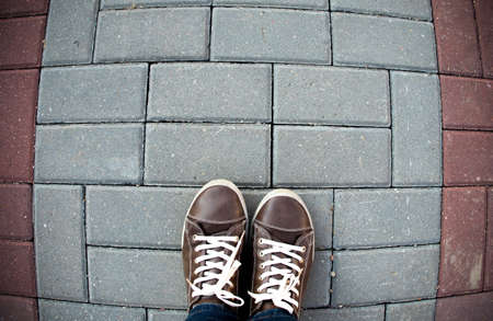 Person taking photo of his feet stand on blank floor, isolated, top view, clipping path. Ground design mock up. Man wearing gumshoes and watching down. Deck floor mockup template.の写真素材