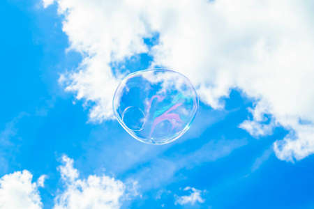 A big bubble floating in the sky, the sky is bright blue behind, the bubbleの写真素材