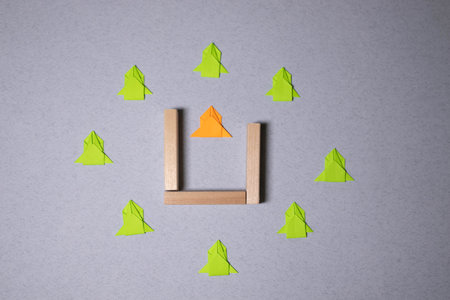Think different concept, hand holding green paper arrow on wooden background.