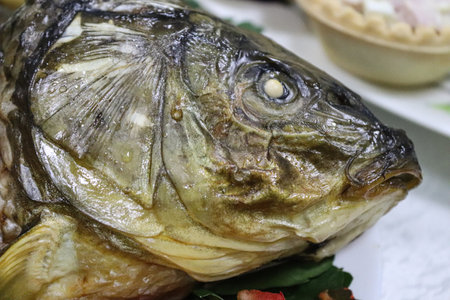 sea bream in salt after baking: detail of the head of the fish buried in salt showing the open mouth and teeth.の写真素材