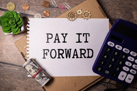 Text PAY IT FORWARD on a notebook with office tools on white background.の写真素材