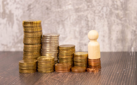 Miniature businessman on top of a pile of coins with construction workers, leadership, success concept.の写真素材