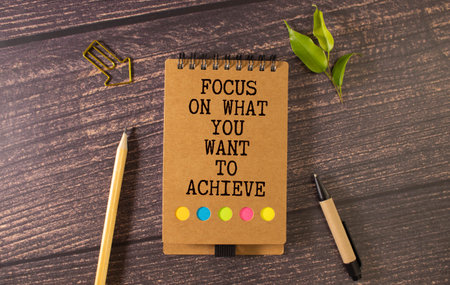 Retro effect and toned image of a woman hand writing a note with a fountain pen on a notebook. Handwritten text Focus On What You Want To Achieve as business concept imageの写真素材
