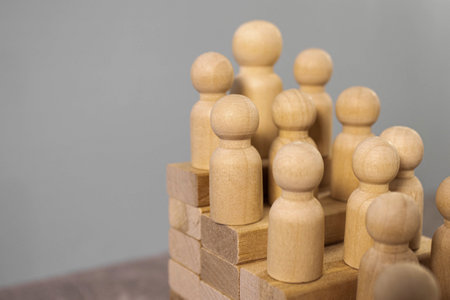 Career stair concept. Wooden people figures as employers on stair made of wooden cubes on gray backgroundの写真素材