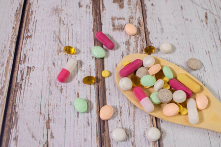 Assorted pharmaceutical medicine pills, tablets and capsules on wooden spoon.の写真素材