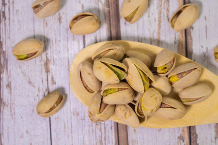 Pistachio nuts are in a wooden spoon placed on a wooden table.の写真素材