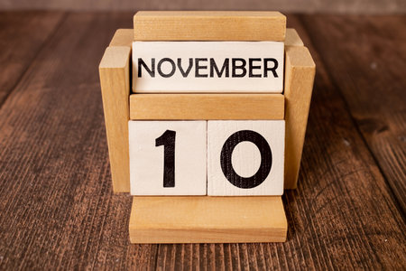 November calendar background with number 10. Stationery pens and pencils in a case on a wooden vintage background. Copy space notepad with pencils and calendar. Planner place for text.の写真素材
