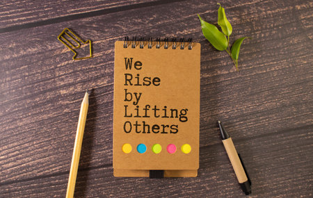 Concept of We Rise By Lifting Others write on paperwork isolated on Wooden Tableの写真素材