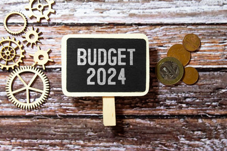 money in a glass jar and a sprout, labeled BUDGET 2024.の写真素材