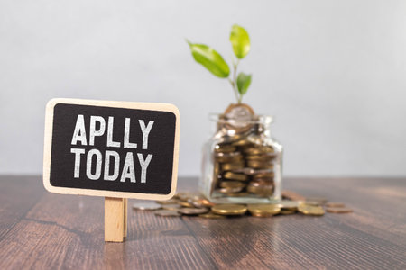 a jar of coins and apply today on a black plaqueの写真素材