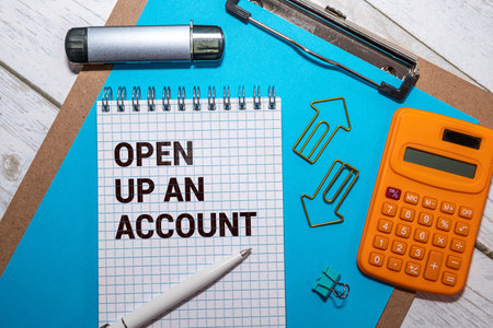 Text OPEN UP AN ACCOUNT on white paper on clipboard with chart and calculatorの写真素材