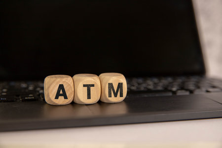 Denia, Alicante - Spain - 12-22-2023: Person using an ATM with a blue screen displaying large 'ATM'...