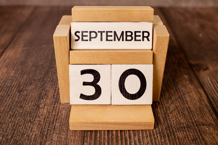 September 30 on a wooden calendar next to the alarm clock.September day, empty space for text.Calendar for September on a light backgroundの写真素材