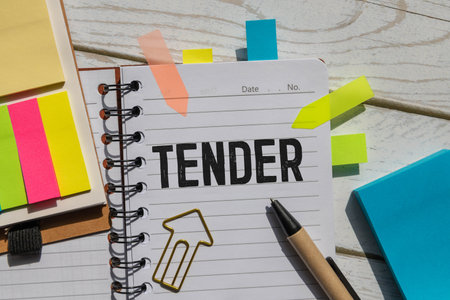 TENDERS lie near a cup of coffee. text on a notebook.の写真素材