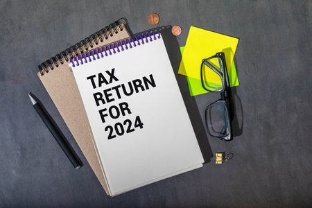 White paper sheet with text INCOME TAX RETURN 2024 on the black laptop.の写真素材
