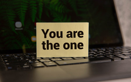 Wooden clothespin with white sheet of paper. Text 'you are not alone'. Beautiful wooden background....