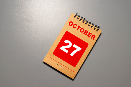 Wooden calendar with the date October 27 on desktop with laptop.