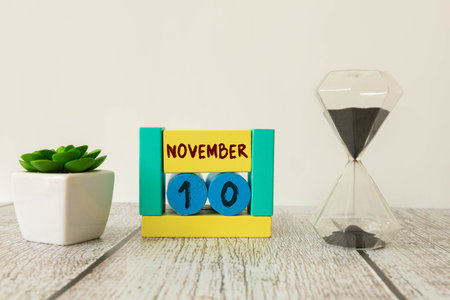 November 10th. Image of november 10 wooden color calendar on white background. Day 10 of November month. Business calendar. Calendar and leaves isolated white. Eco friendly, ecology, Sustainable date.の写真素材