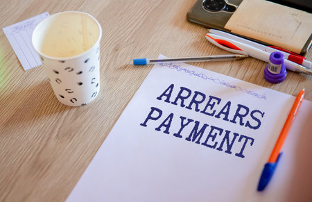 Business and finance concept. On the table are a pen and a notebook with the inscriptions - Arrears.