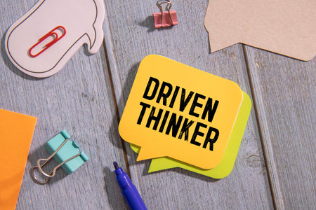Closeup on businessman holding a card with text DRIVEN THINKER, business concept image with soft focus background and vintage toneの写真素材