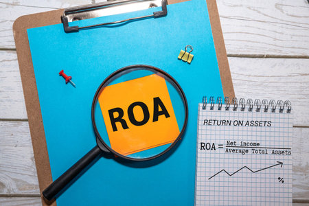 ROA - short for Return On Assets. text on wood cubes with euro bills. front view