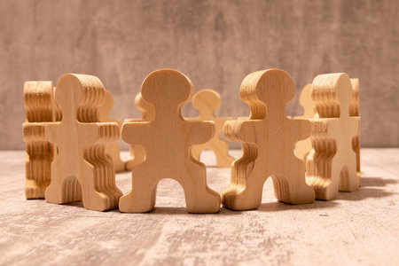 Many different paper human figures standing in circle on wooden table against beige background.の写真素材