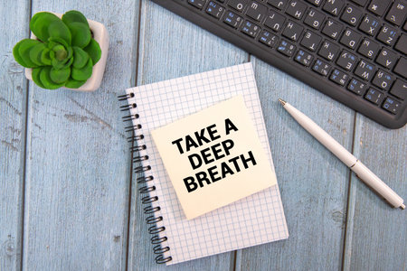 Words of Take Deep Breath on sticky color papers hanging by a rope against blurred green background.