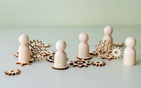 People figures as workers on connected gear wheels. Teamwork and togetherness concept.の写真素材