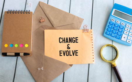 The text CHANGE EVOLVE written on a piece of paper of a notebook standing on the tableの写真素材