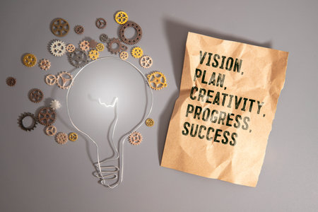 Male hand placing a block with the word 'success' on top of a blocks tower with words 'vision, plan, creativity, progress'. Wooden table. Beautiful white background. Copy space, business concept.の写真素材