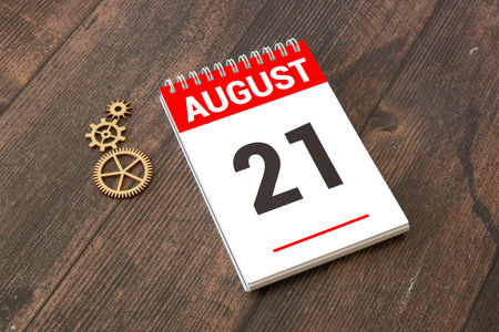 Wooden block calendar with the date August 21 and spikelets of wheat on a beige concrete background
