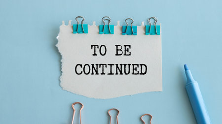 To Be Continued text message and binder clips on blue background.の写真素材