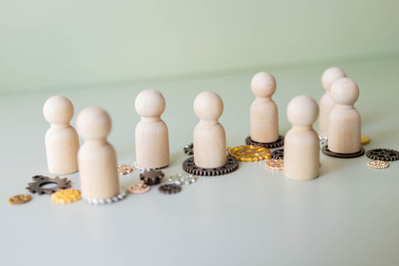 A conceptual image with wooden figures standing on interconnected gears. Teamwork, collaboration,...