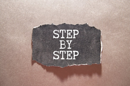 The words NEXT STEPS is written in a notebook near multi-colored pencils and buttons on a wooden...