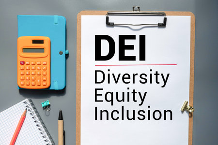 Modern laptop with text DIVERSITY, EQUITY, INCLUSION on screen at workplace