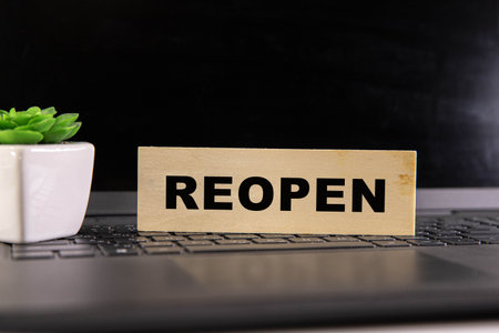 Reopen concept after the coronavirus pandemic. Hand flip over wooden cubes with text REOPEN on blue background.の写真素材