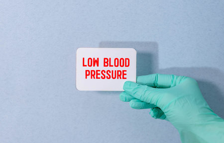 Paper with text LOW BLOOD PRESSURE on a table with stethoscope. Medical concept