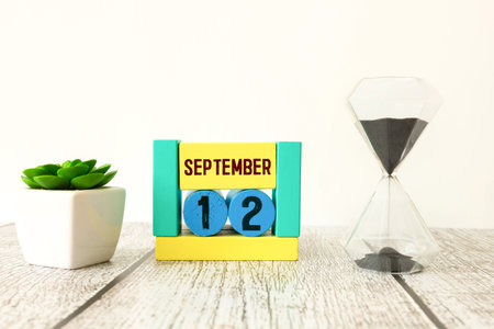 Wooden calendar with the date September 12.Monthly calendar for planning and management concept with alarm clock on wooden backgroundの写真素材